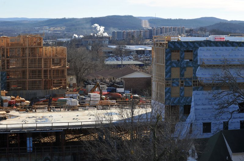FILE PHOTO &#8212; Construction crews work on the Cardinal apartment complex on Duncan Avenue and Center Street in Fayetteville in January. The Vue apartment complex that opened for the fall semester can be seen on the hill behind the five-story Cardinal complex located a block from the University of Arkansas campus.