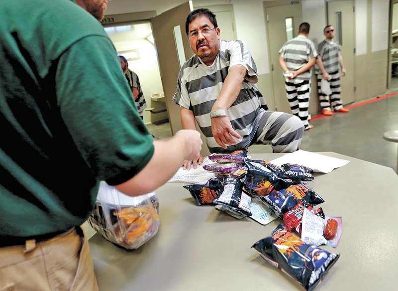 FILE PHOTO JASON IVESTER Commissary Manager Matt Etris checks the identification on Marcelino Pacheco before distributing items at Benton County&#8217;s jail on Oct. 9 in Bentonville. The state Legislature didn&#8217;t increase money paid to county jails to house prisoners in the recent fiscal session.
