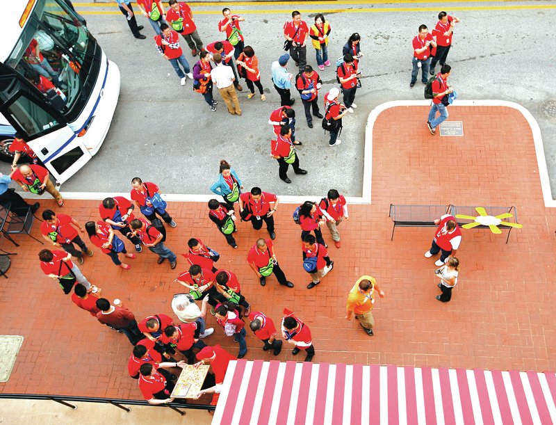 FILE PHOTO JASON IVESTER Walmart employees from China exit their buss outside the Walmart Visitors Center June 4 in downtown Bentonville.