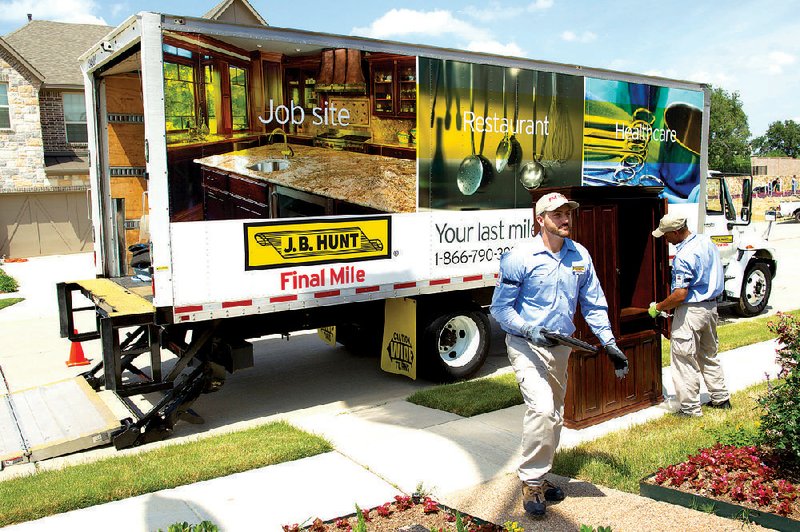 Gary Shutter (left) and Bernard Telsa make a delivery in Dallas for J.B. Hunt’s new service, Final Mile. The service provides home delivery of appliances, furniture and other goods. 