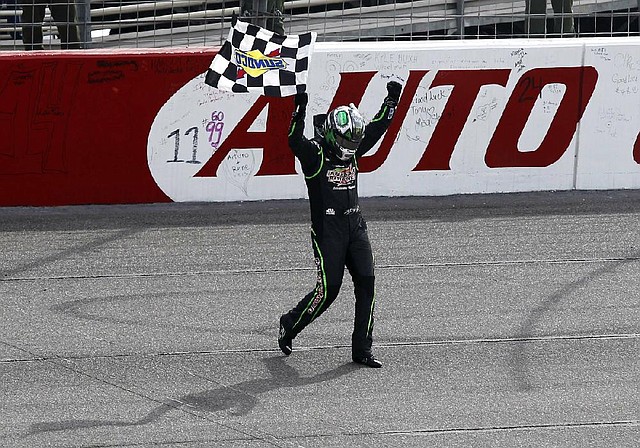 Kyle Busch (18) celebrates with the checkered flag after winning the NASCAR Sprint Series auto race in Fontana, Calif., Sunday, March 23, 2014. (AP Photo/Alex Gallardo)