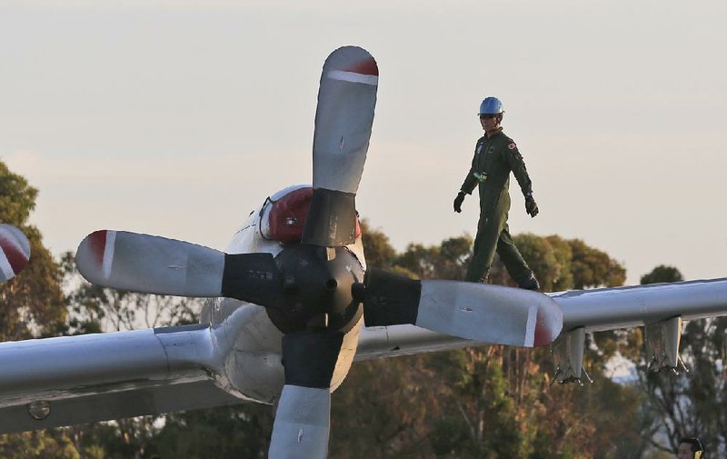A technician walks on the wing of a Japan Maritime Self-Defense Force P-3C Orion aircraft after its arrival to help with search operations for the missing Malaysia Airlines Flight MH370, at Royal Australian Air Force Pearce Base in Perth, Australia, Sunday, March 23, 2014. (AP Photo/Rob Griffith, Pool)