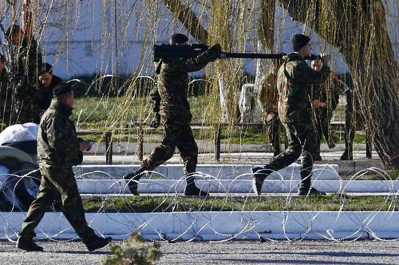 Ukrainian marines carry a machine gun inside the Ukrainian marines base in the city of Feodosia, Crimea, Sunday, March 23, 2014. On Sunday, the Russian Defense Ministry said the Russian flag was now flying over 189 military facilities in Crimea. It didn't specify whether any Ukrainian military operations there remained under Ukrainian control. (AP Photo/ Pavel Golovkin)