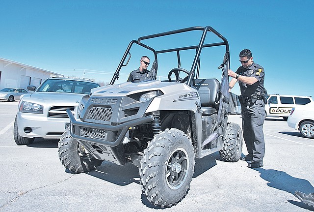 STAFF PHOTO ANTHONY REYES Cpl. Jared Pena, checks out the bed of an electric Polaris Ranger off-road vehicle March 13 at the Springdale Police Department in Springdale. The city is looking at buying small vehicles for use on trails.