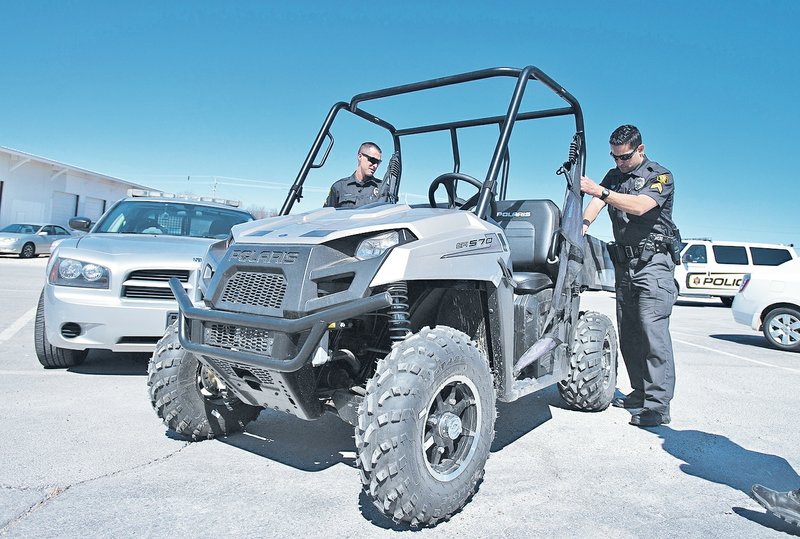 STAFF PHOTO ANTHONY REYES Cpl. Jared Pena, checks out the bed of an electric Polaris Ranger off-road vehicle March 13 at the Springdale Police Department in Springdale. The city is looking at buying small vehicles for use on trails.