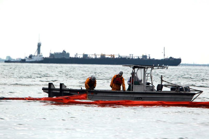 A work crew drops a boom into Galveston Bay on Monday to prevent crude from reaching the shores of Galveston, Texas. The Coast Guard on Tuesday partially reopened the Houston Ship Channel after a barge spilled up to 170,000 gallons of fuel oil after colliding with a ship Saturday. 
