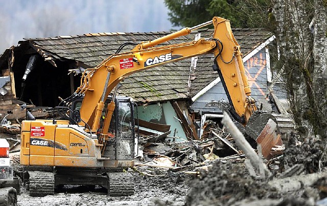 Workers use heavy equipment to clear debris Tuesday from a highway on the western edge of the mudslide that struck near Arlington, Wash. 