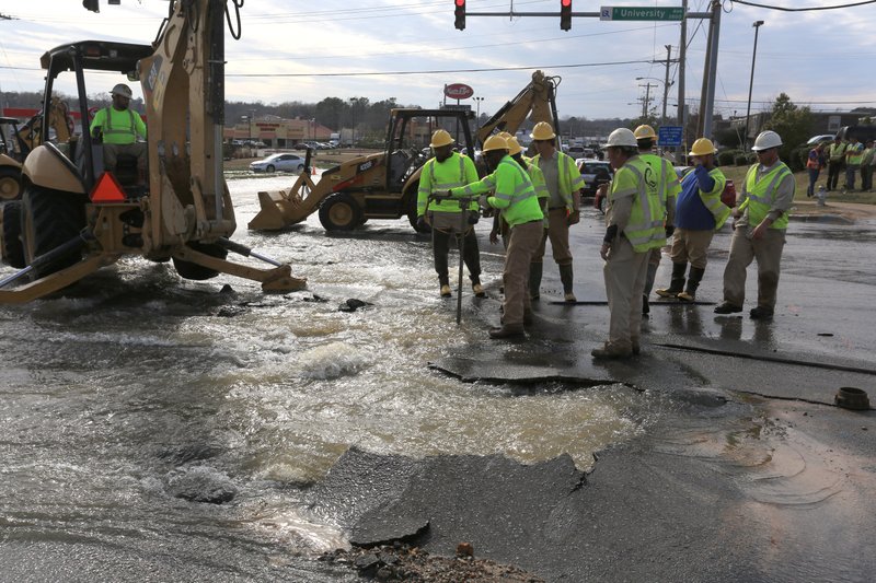 Central Arkansas Water crews work a stop the flow of water from a busted water main at the intersection of South University Avenue and Asher Avenue in Little Rock Wednesday evening. Traffic was being diverted and not allowed into the intersection.