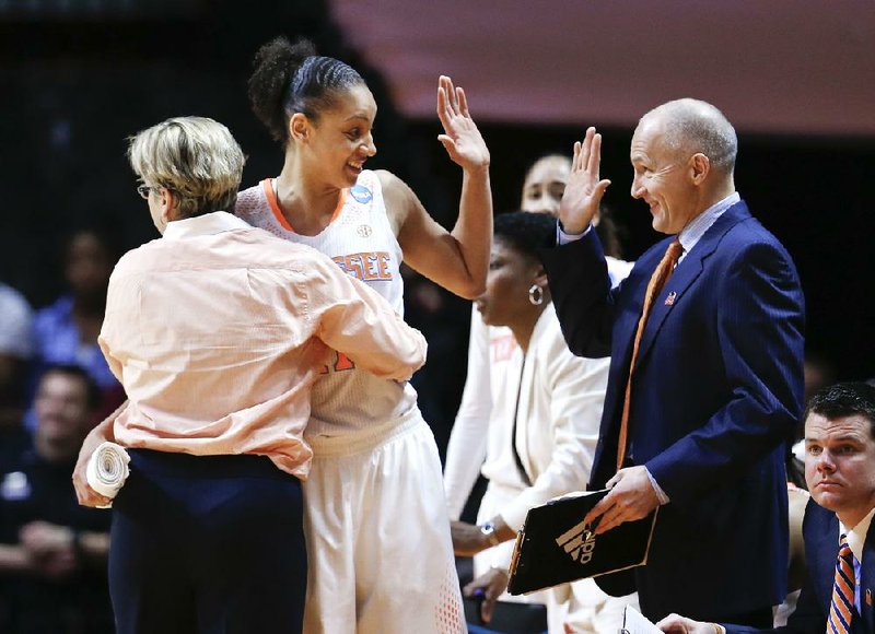 Tennessee forward Cierra Burdick, center, is hugged by head coach Holly Warlick, left, and slaps hands with assistant coach Dean Lockwood, right, as Burdick leaves the game late in the second half an NCAA women's college basketball second-round tournament game against St. John's Monday, March 24, 2014, in Knoxville, Tenn. Burdick led Tennessee with 21 points as they won 67-51. (AP Photo/John Bazemore)