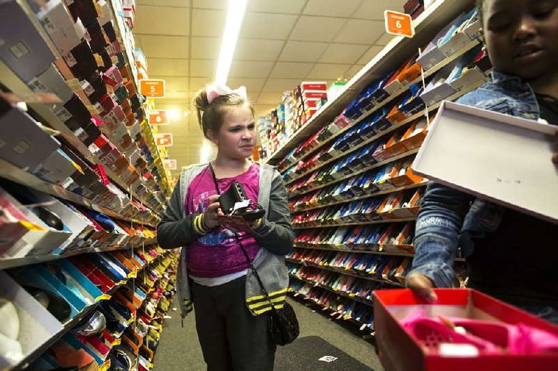 Zadie Farrell, 10, (left) and Amaiya Thornton, 8, pick out shoes at a Payless ShoeSource store at 11400 W. Markham St. in Little Rock on Thursday. Our House took 55 children who are enrolled in the homeless shelter’s out-of-school program to the store, where they were treated to a pair of shoes. 