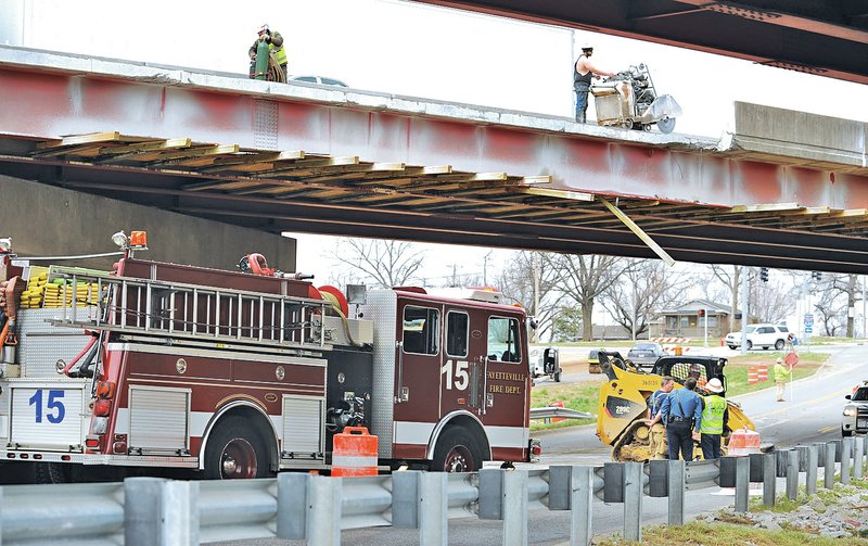 STAFF PHOTO ANDY SHUPE Fayetteville Fire Department personnel and Arkansas State Police assist Thursday as crews clean debris on Porter Road in Fayetteville after a report a worker fell from the Interstate 540 overpass to the road below.