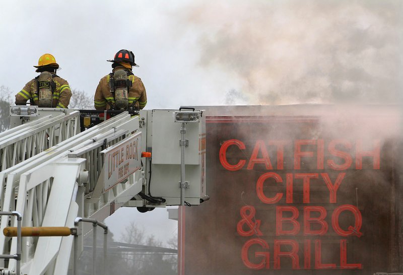 Little Rock firefighters use a ladder truck to access the roof of Catfish City on University Ave. while responding to a fire in the restaurant on Friday afternoon.