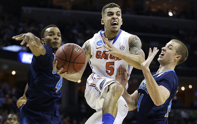 Florida guard Scottie Wilbekin (5) flies by UCLA guard Norman Powell (4) and UCLA forward Travis Wear, right, during the first half in a regional semifinal game at the NCAA college basketball tournament, Thursday, March 27, 2014, in Memphis, Tenn. (AP Photo/Mark Humphrey)