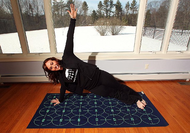 In this March 7, 2014 photo, Elizabeth Morrow poses on her specially designed Yoga by Numbers mat in Bow, N.H. The mat gives true yoga beginners a step-by-step roadmap to learn poses at their own pace. (AP Photo/Jim Cole)