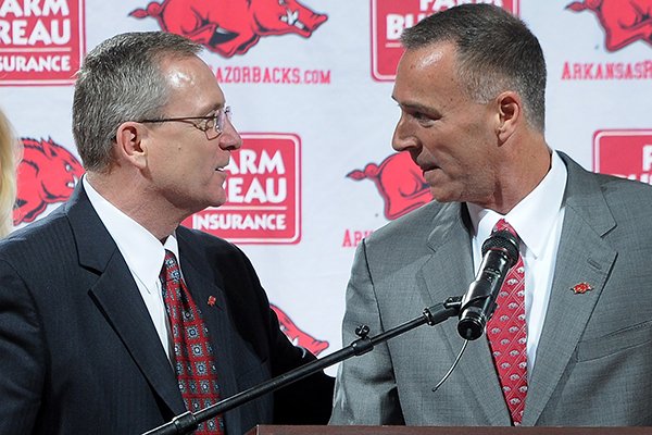 Jeff Long, director of athletics and vice chancellor, left, congratulates Jimmy Dykes after being introduced as the eighth women's head basketball coach Sunday, March 30, 2014, at Bud Walton Arena in Fayetteville.