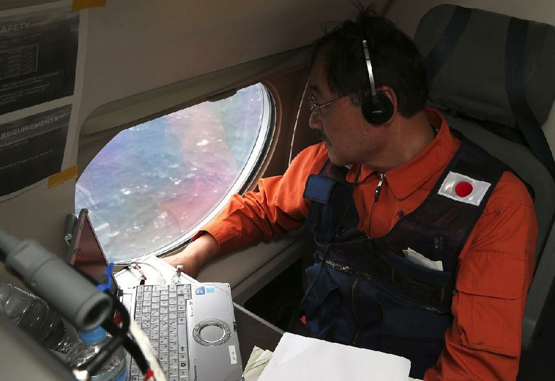 Hidetaka Sato, communications specialist on a Japan Coast Guard Gulfstream aircraft, looks out of a window searching for the missing Malaysia Airlines Flight 370 in the southern Indian Ocean. 