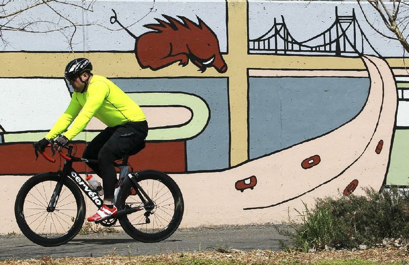 A cyclist rides past a mural in North Little Rock’s Riverfront Park on Tuesday as Arkansas officials discuss ways to improve the state’s bicycle- and pedestrian-friendly ranking. 