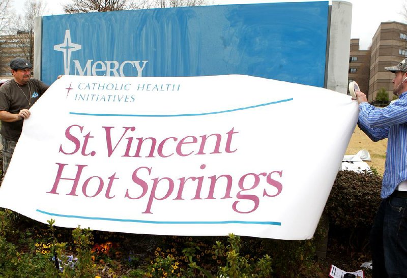 Doug Hethcox (left) and Kyle McCabe of Ace Sign Co., put up a new sign Tuesday outside the former Mercy Hot Springs hospital after St. Vincent Health System announced its acquisition of the hospital. 