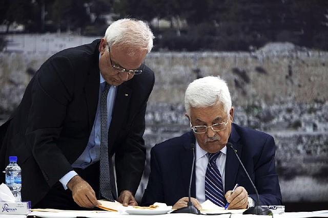 Palestinian President Mahmoud Abbas (seated), joined by Palestinian chief peace negotiator Saeb Erekat, signs an application to join U.N. agencies in the West Bank city of Ramallah on Tuesday. 