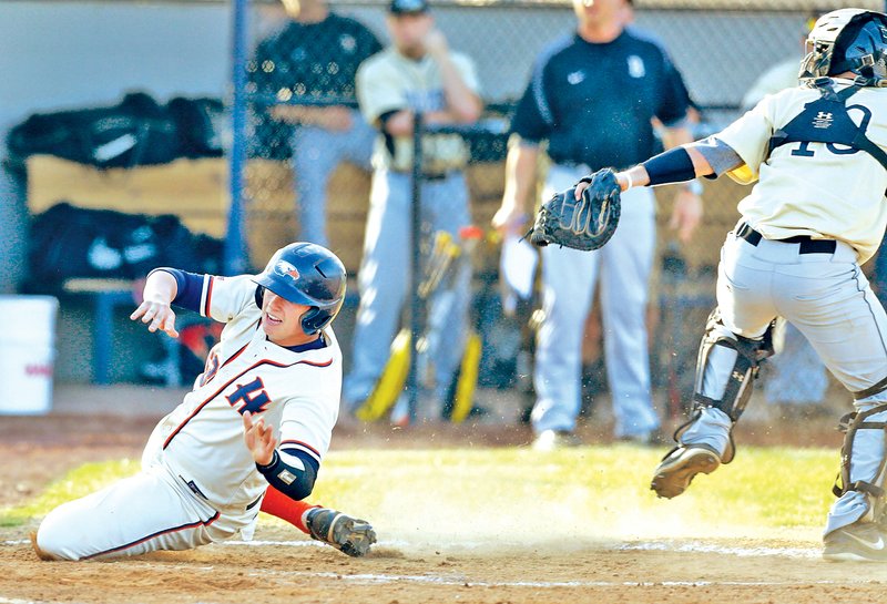 STAFF PHOTO JASON IVESTER Colton Wetzler of Rogers Heritage safely slides past the tag attempt Tuesday from Bentonville catcher Kane Koenigseder for a run at Veterans Park in Rogers.
