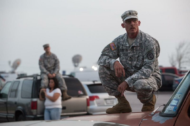 Staff Sgt. John Robertson waits with other soldiers and family members Wednesday outside their post at Fort Hood, Texas, for updates about the situation inside. 