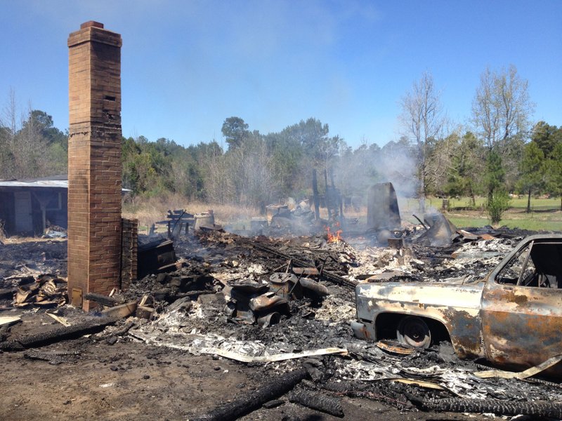 Fire smolders in the remains of a Dallas County home off Arkansas 7, just north of Sparkman, on Friday afternoon. Two children died in the early-morning fire, which authorities say was caused by candles that were lit after the home lost power in Thursday night's storms.