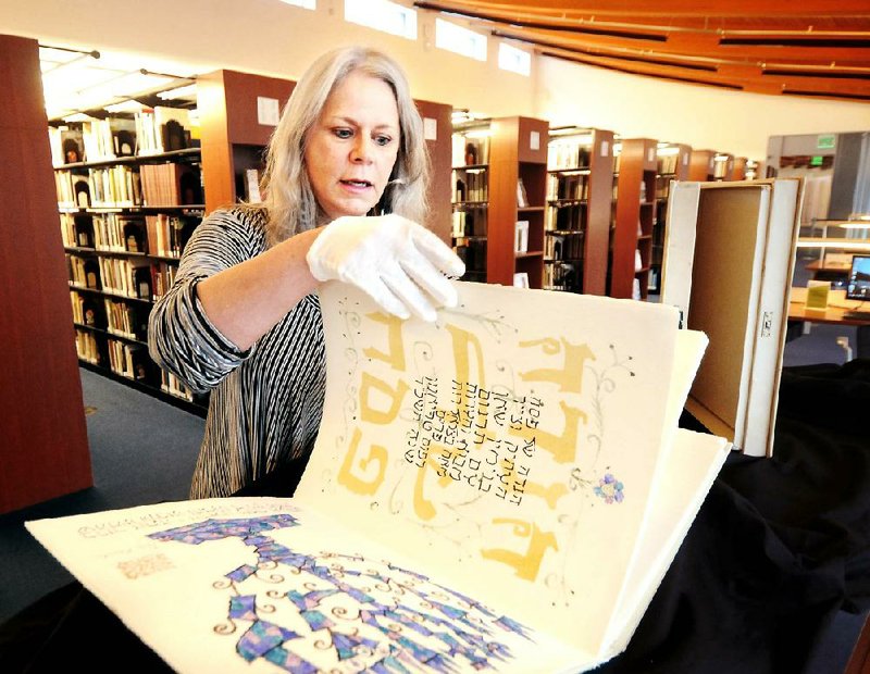 Catherine Petersen, library director at Crystal Bridges Museum of American Art, flips through the pages of a rare, first edition Haggadah for Passover. The book, featuring watercolor drawings by artist Ben Shahn, will be the subject of a talk by Rabbi Jack Zanerhaft on Monday at the museum. 