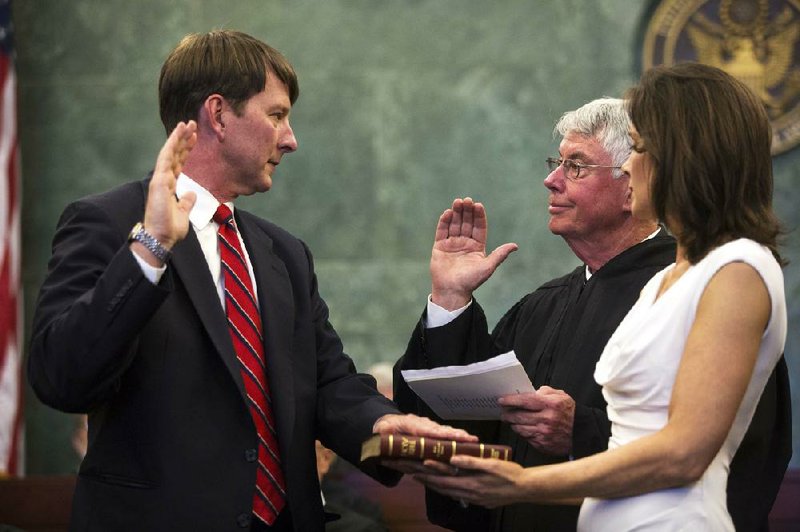 In this 2014 file photo U.S. District Judge James Moody Jr takes an oath while placing a hand on a Bible held by his wife Melinda and answers to his father James M. Moody Sr. 