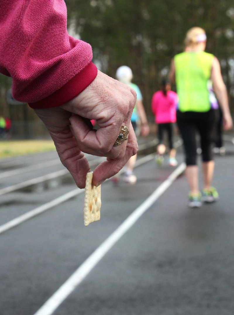 Democrat-Gazette photo illustration/CELIA STOREY
Coreen Frasier holds a saltine cracker on the track at J.A. Fair High School during a workout with the Women Run Arkansas running and walking clinic on March 31, 2014.
