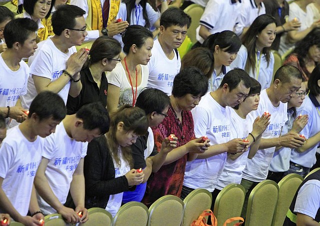 Chinese relatives of passengers aboard Malaysia Airlines Flight 370 hold LED candles as they offer prayers during a mass prayer for the missing plane, in Kuala Lumpur, Malaysia, Sunday, April 6, 2014. The head of the multinational search for the missing Malaysia airlines jet said that electronic pulses reportedly picked up by a Chinese ship are an encouraging sign but stresses they are not yet verified. The writing on the t-shirts reads "Praying that MH370 returns home safely." (AP Photo/Lai Seng Sin)