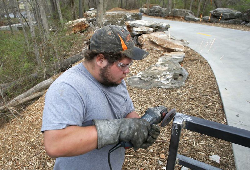 NWA Media/DAVID GOTTSCHALK - 4/3/14 -  Mickey Prather, with FenceCo, Inc. of Fayetteville, rounds out the edges of a weld on the hand rails on the new section of the Clear Creek Trail near Lake Fayetteville Thursday April 3, 2014. Part of the Fayetteville portion of the Razorback Greenway, the portion will officially open April 12 with ribbon-cuttings.
