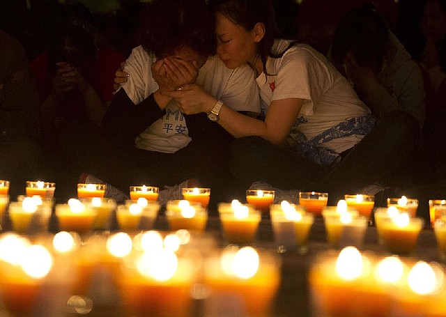 A woman comforts another as they attend a candlelight vigil for their loved ones with other relatives of Chinese passengers onboard the missing Malaysia Airlines Flight 370 at a hotel in Beijing, China, Tuesday, April 8, 2014. An Australian ship detected two distinct, long-lasting sounds underwater that are consistent with the pings from aircraft black boxes in a major break in the month long hunt for the missing Malaysia Airlines jet, the search coordinator said Monday, April 7, 2014. (AP Photo/Andy Wong)