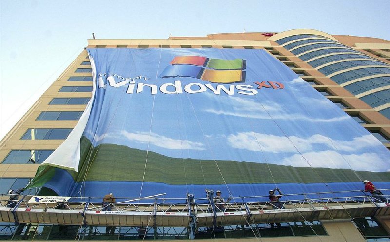 FILE - In this Nov. 8 2001 file photo, workers install a 10-story Windows XP banner on a hotel near the Las Vegas Convention Center in Las Vegas. On Tuesday, April 8, 2014, Microsoft will end support for its still popular Windows XP. With an estimated 30 percent of businesses and consumers still using the 12-year-old operating system, the move could put everything from the data of major financial institutions to the identities of everyday people in danger if they don’t find a way to upgrade soon. (AP Photo/Joe Cavaretta, File)