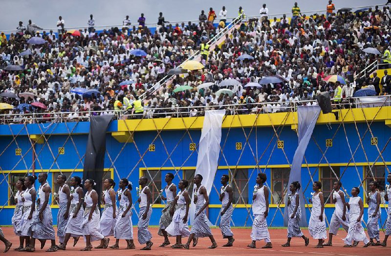 Performers re-enacting some of the events enter a public ceremony to mark the 20th anniversary of the Rwandan genocide, at Amahoro stadium in Kigali, Rwanda Monday, April 7, 2014. Sorrowful wails and uncontrollable sobs resounded Monday as thousands of Rwandans packed the country's main sports stadium to mark the 20th anniversary of the beginning of a devastating 100-day genocide. (AP Photo/Ben Curtis)