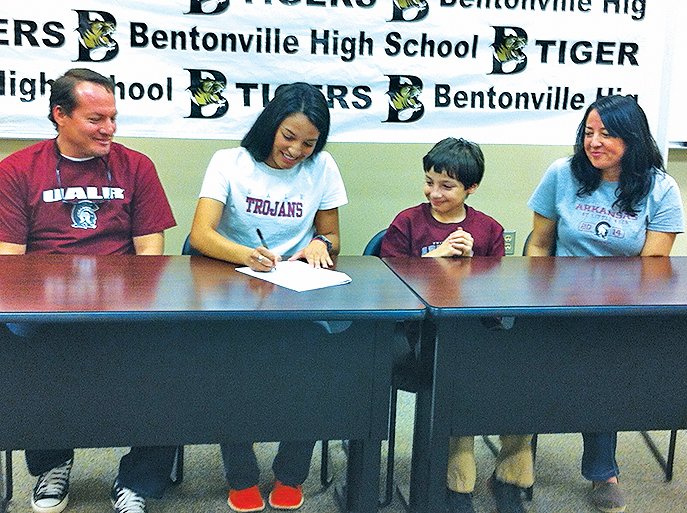 STAFF PHOTO HENRY APPLE Rebeca Solis (second from left) of Bentonville signs her national letter of intent to run track and cross country with Arkansas-Little Rock during Monday's ceremony at the Tiger Athletic Complex. She is joined by her father Herbert Solis (from left), brother Matthew and mother Maritza Solis.