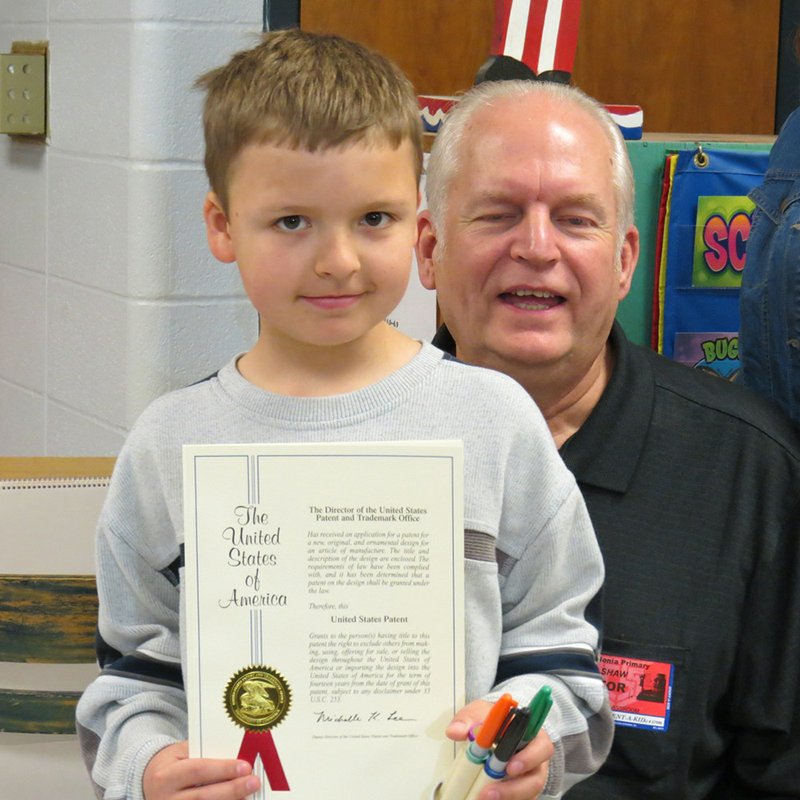 Four-grader, Zane Parker stands with his grandfather, David Shaw while holding his U.s. patent and shi handmade desktop organizer.