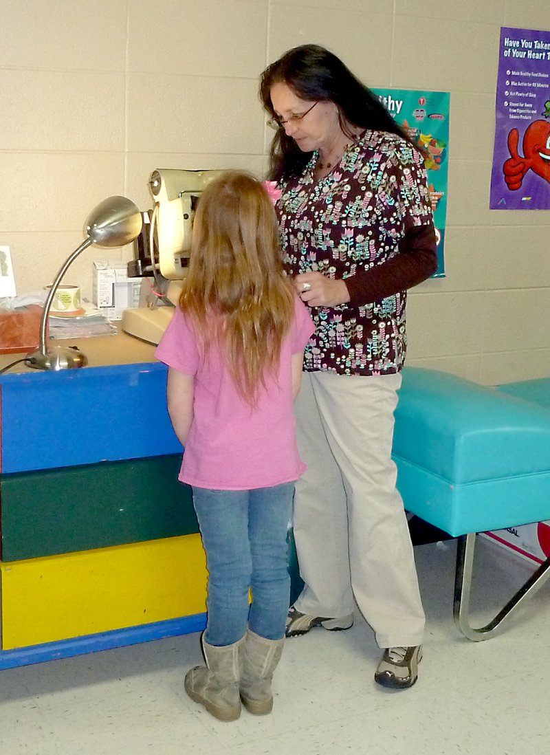 Submitted Photo School nurse Wendy Catron, RN, assists a student at Glenn Duffy Elementary School in Gravette.