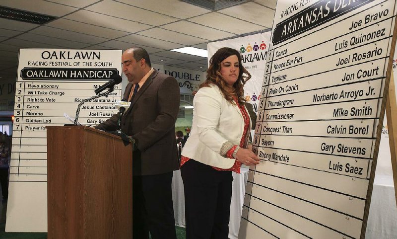 Oaklawn Park track announcer Frank Mirahmadi (left) announces the final post position for Saturday’s $1 million Arkansas Derby as marketing manager Sara Jeffers places the horse’s name on the board. 