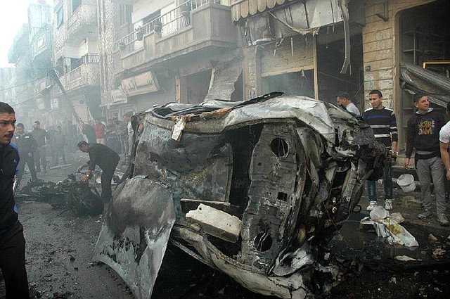 Syrians gather Wednesday at the site where two car bombs exploded at a commercial street in the city of Homs that is inhabited mostly by members of President Bashar Assad’s Alawite sect. 