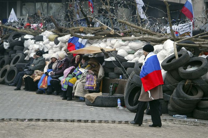 A woman wrapped in a Russian flag walks past a barricade Wednesday in Donetsk, one of the eastern Ukrainian regions where pro-Russian protesters are occupying government buildings. 