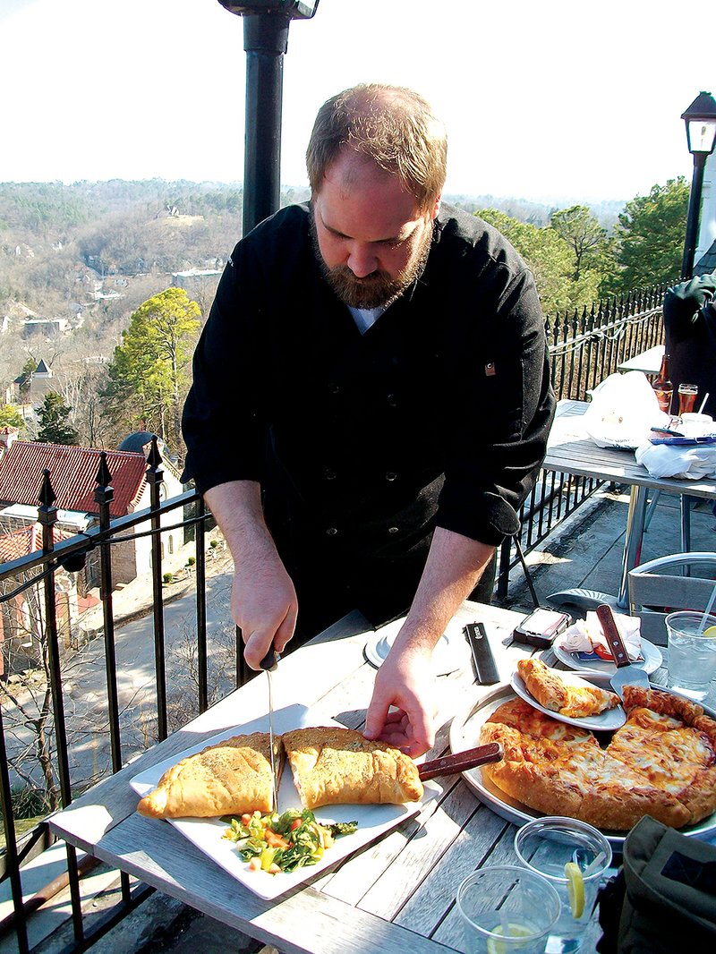 STAFF PHOTO ALLISON CARTER 
Lee Brooks, new executive chef at the 1886 Crescent Hotel and Spa in Eureka Springs, cuts into the “almost world famous” crescent-shaped calzone offered at the Sky Bar restaurant at the hotel. The University of Arkansas graduate just started his new job a few weeks ago.