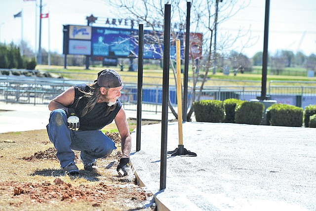 STAFF PHOTO ANTHONY REYES Mark Lee with National Greens of Little Rock checks the level of rock for a base Wednesday for a artificial turf Wiffle ball field at Arvest Ballpark in Springdale. The new field is one of the attractions offered to families at the ballpark during games. The Northwest Arkansas Naturals open their home season today.