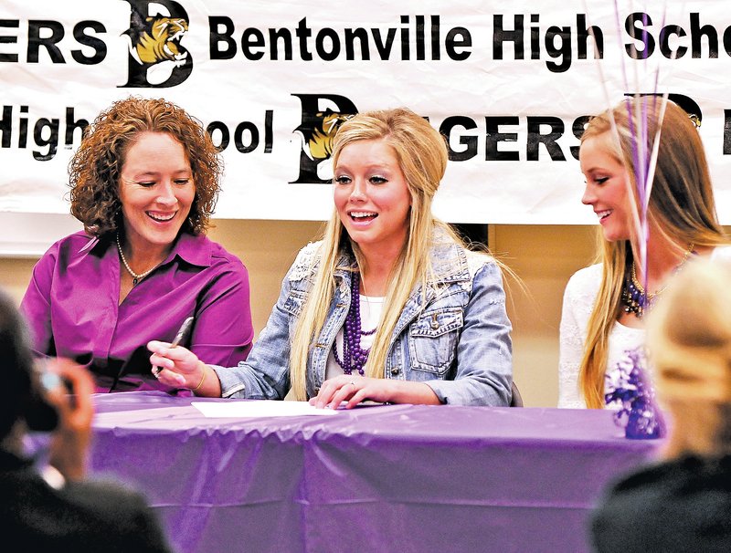  STAFF PHOTO BEN GOFF Logan Morton, center, Bentonville High track athlete, flanked by her mother, Miranda Hagans, left, and sister, Morgan Morton, signs a national letter of intent with the University of Central Arkansas during a ceremony Wednesday in Bentonville's Tiger Athletic Complex.