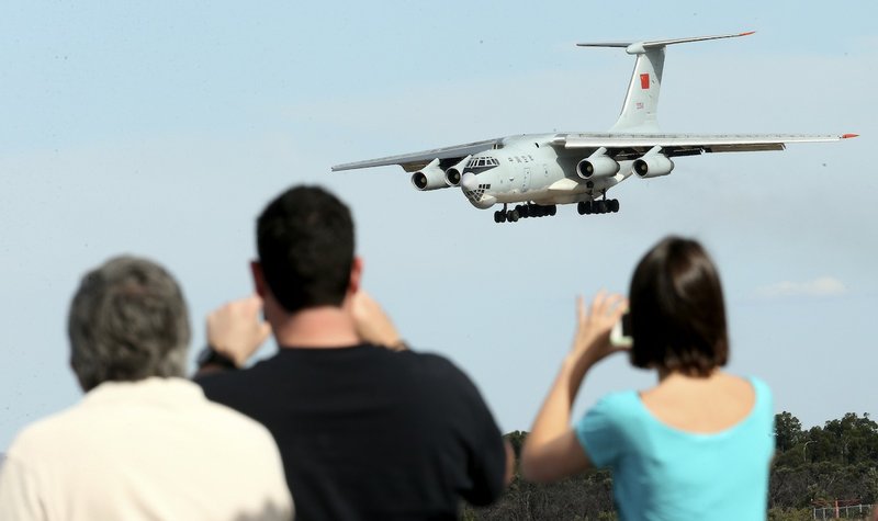 Spectators take photos of a Chinese Ilyushin IL-76 aircraft as it comes in for a landing at Perth International Airport after returning from the ongoing search operations for missing Malaysia Airlines Flight 370 in Perth, Australia, Thursday, April 10, 2014.