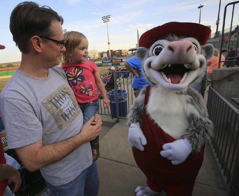 Arkansas Democrat-Gazette/STATON BREIDENTHAL --4/10/14-- Mike Sims (cq) holds daughter Keira Sims, 2,  as they meet the Arkansas Travelers new mascot, Otey the Swamp Possum, Thursday night at Dickey-Stephens Park in North Little Rock. 