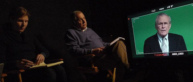A production assistant (left) takes notes as director Errol Morris interviews former Secretary of Defense Donald Rumsfeld (shown on screen) for his documentary The Unknown Known. 
