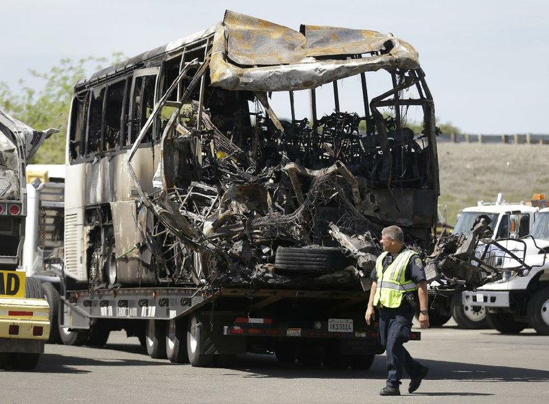 A Highway Patrol officer in Willows, Calif., on Friday walks past the charred remains of the tour bus involved in Thursday’s deadly accident on a California highway. 