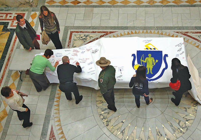 The Associated Press TRAGEDY REMEMBERED: People sign the America 4 Prayer Canvas in remembrance of the 2013 Boston Marathon bombing victims and survivors on Friday at the Statehouse in Boston. Three people were killed and more than 260 injured in the bombing.