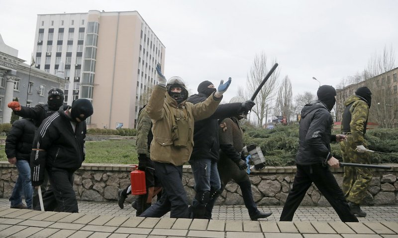 Masked pro-Russian activists march after leaving a regional prosecutor's office in Donetsk, Ukraine, Saturday, April 12, 2014. Saturday morning a group of pro-Russian activists armed with metal sticks seized the office. Later they left the building after talks with police. Nobody was arrested. 