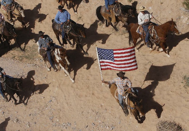 The Bundy family and its supporters watch from their horses Saturday outside Bunkerville, Nev., as Bureau of Land Management employees release back onto public land the 400 cattle they had rounded up and held that belong to Cliven Bundy. 